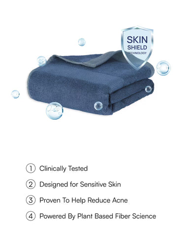 Folded blue towel with 'Skin Shield' technology label and water droplets on a white background