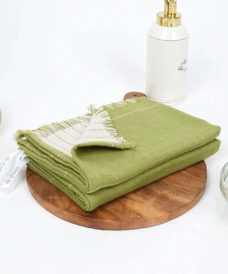 Aloe green towel on a wooden board with a white container in the background
