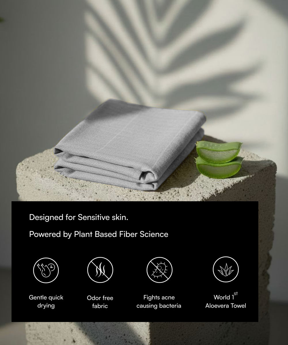 Gray towel on a stone surface with aloe vera leaves, labeled as sensitive skin product.