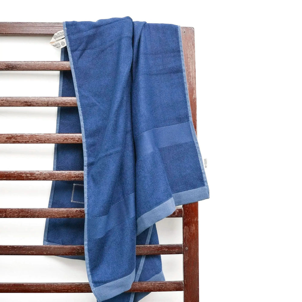 French blue towel draped over a wooden towel rack on a white background