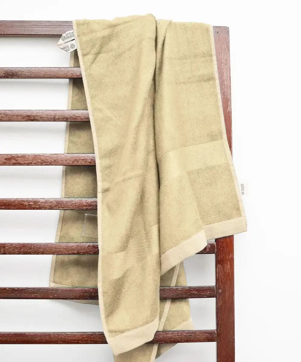 Beige towel draped over a wooden towel rack on a white background.
