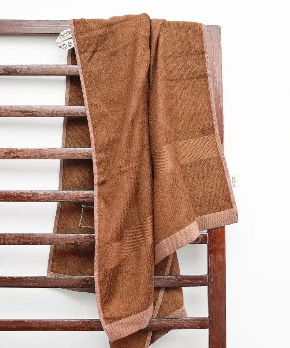 Bombay Brown towel draped over a wooden radiator against a white background