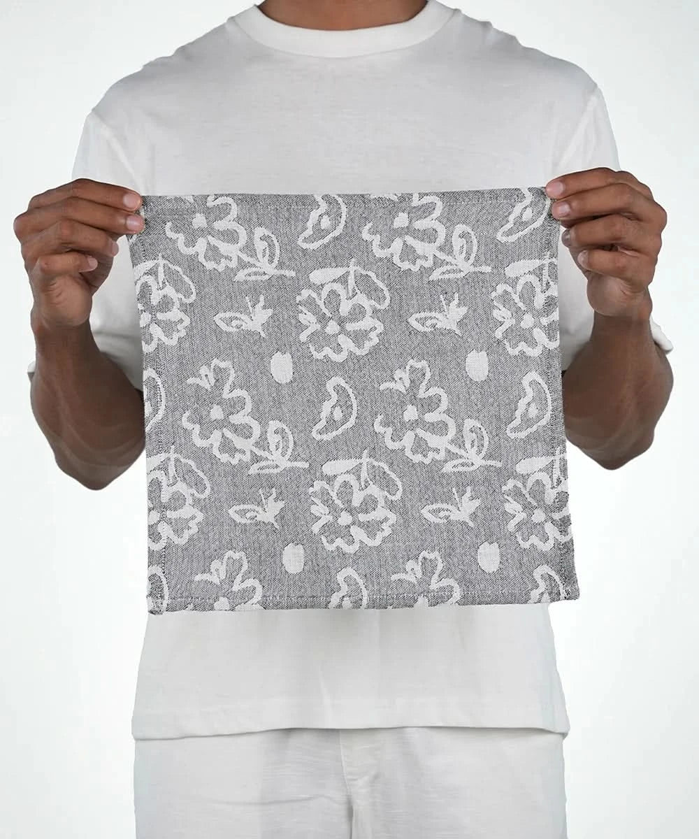 Person holding a gray fabric with white floral pattern against a white background