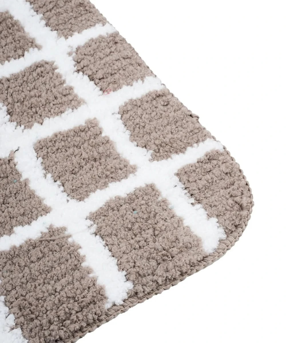 Close-up of a checkered bath mat with a geometric pattern on a white background