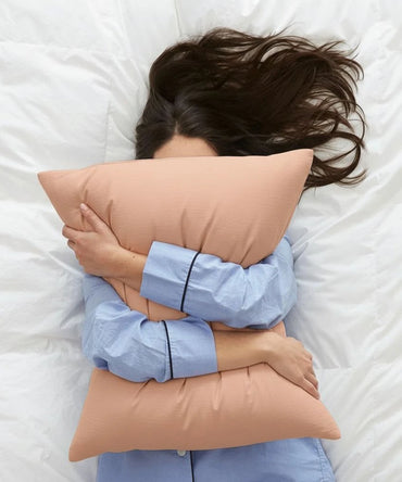 Person lying on a bed with a honey peach colored pillow