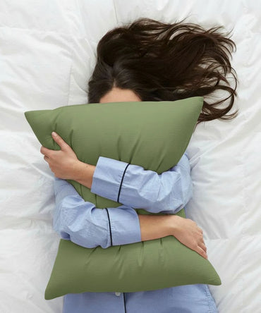Person lying on a bed with a aloe green pillow - House of Doctor