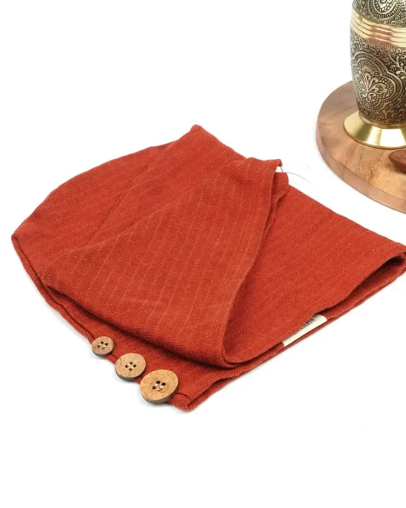 Folded terracotta banana double cloth hair towel with wooden buttons on a white background