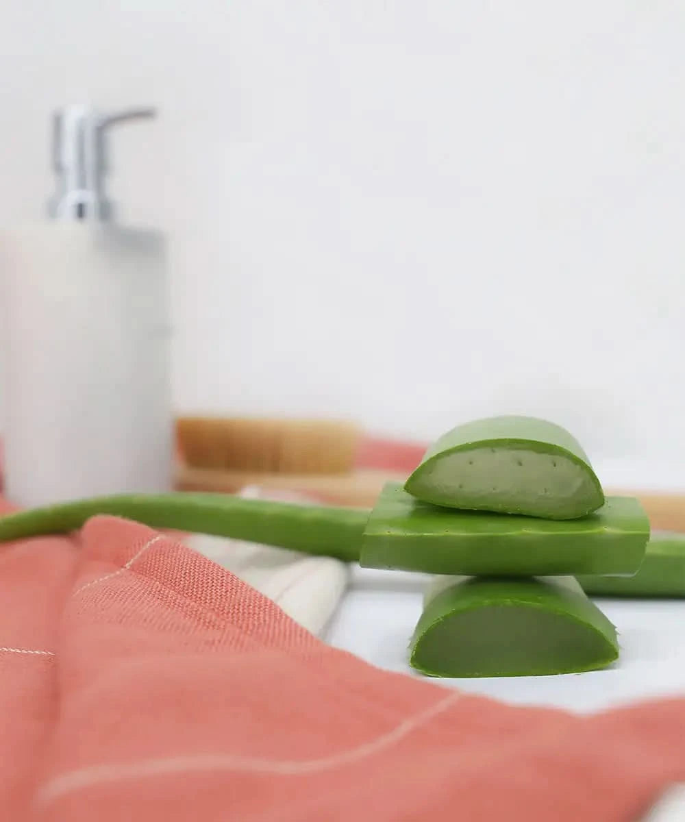 Sliced aloe vera on a white surface with aapricot brandy aloevera towel underneath, blurred background
