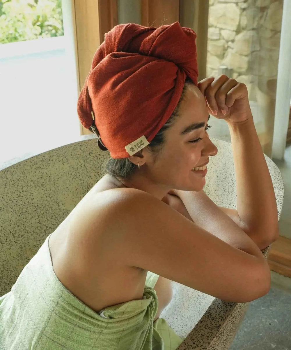 Woman with a terra-cotta banana double cloth hair towel on her head sitting outdoors