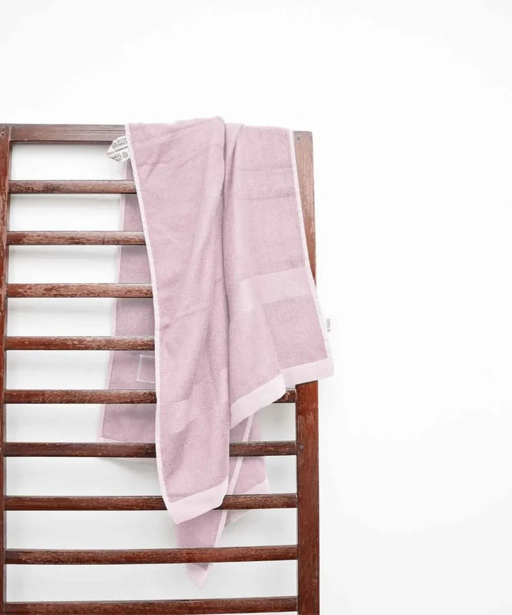 Barely pink towel draped over a wooden ladder against a white background