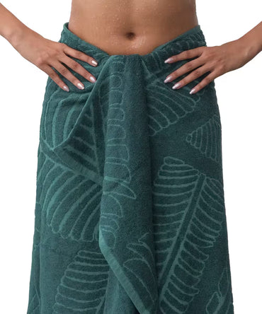 Green towel with leaf pattern draped over a person on a white background