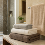 Folded bath towels of different sizes near a towel rod in a bright Indian bathroom