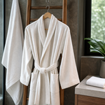 Cotton bath robe hanging in a humid bathroom beside a separate folded face towel and bath towel