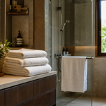 Plush folded white towels in an elegant Indian bathroom with warm light and visible drying setup