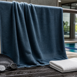 Quick-dry swimming towel hanging beside goggles, a swim cap, and a separate folded face towel
