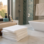 A neat travel and bathroom setup with disposable towels beside a toiletry pouch and sink