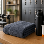 Folded gym towel beside water bottle, sunscreen tube, and gym bag