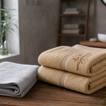 Folded bamboo-toned towels and a separate lighter face towel in a calm Indian bathroom setting