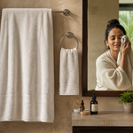 An oversized white bath towel hanging beside a smaller separate face towel in a warm Indian bathroom
