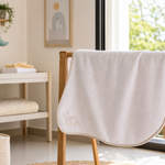Fresh baby towel hanging open to dry in a bright Indian home with nursery details nearby