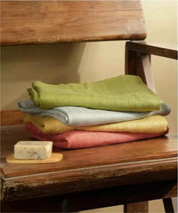 Stack of folded towels on a wooden surface with a bar of soap.
