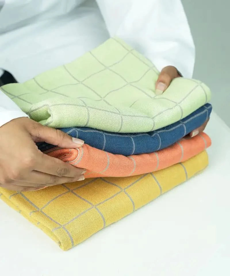 Stack of colorful checkered cloths held by a person on a white background