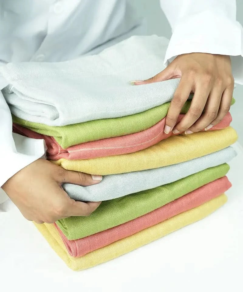 Stack of folded aluvera double cloth bath towels held by a person on a white background