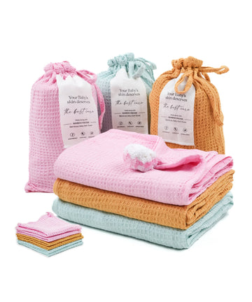 Baby care products including folded towels and small bags on a white background