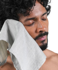Man with a grey towel on his face against a white background