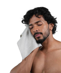 Man with a grey towel on his face against a white background