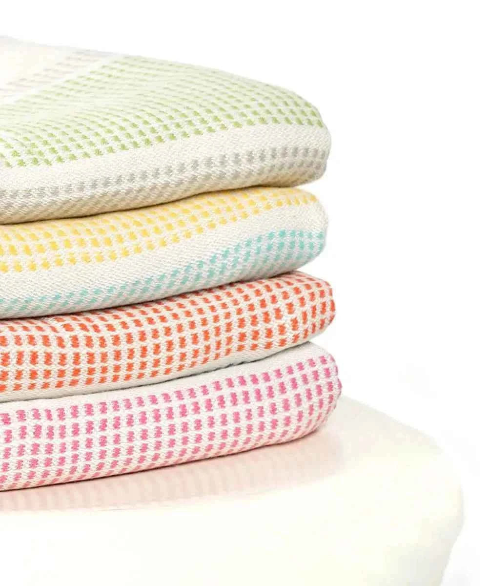 Stack of colorful textured blankets on a white background