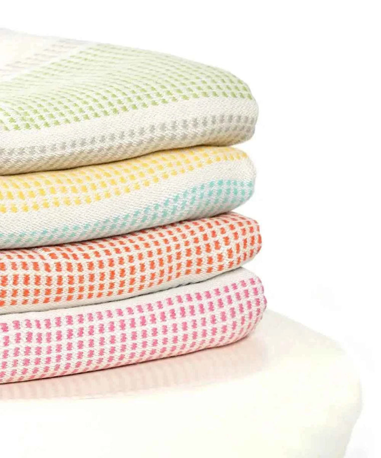 Stack of colorful textured blankets on a white background