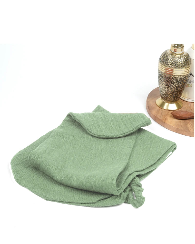 Folded green towel on a white background with a decorative lamp in the corner.