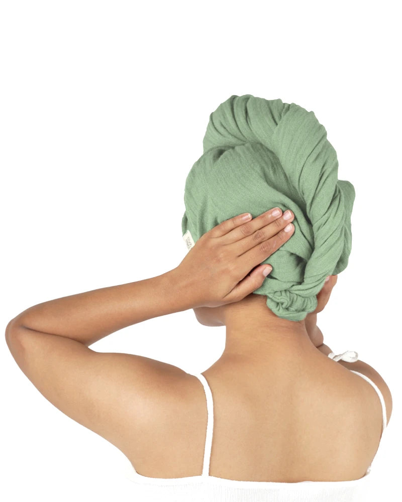 Person wearing a green towel on their head against a white background