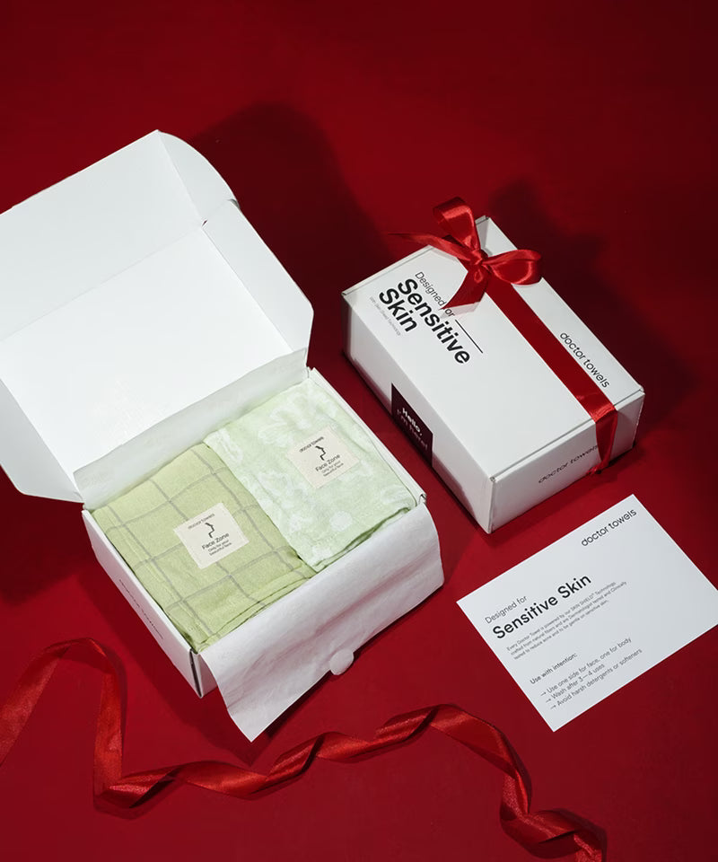 Product packaging with green duo towels, a white box, and a red ribbon on a red background