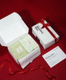 Product packaging with green duo towels, a white box, and a red ribbon on a red background