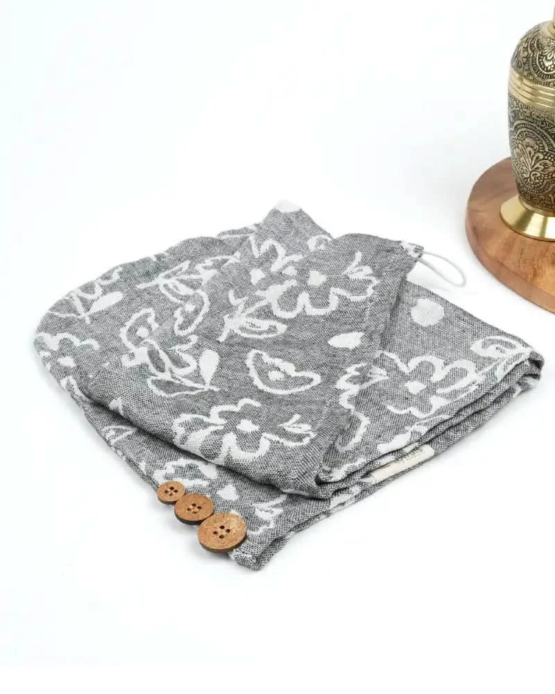 Charcoal grey hair towel with white floral patterns and wooden buttons on a white background