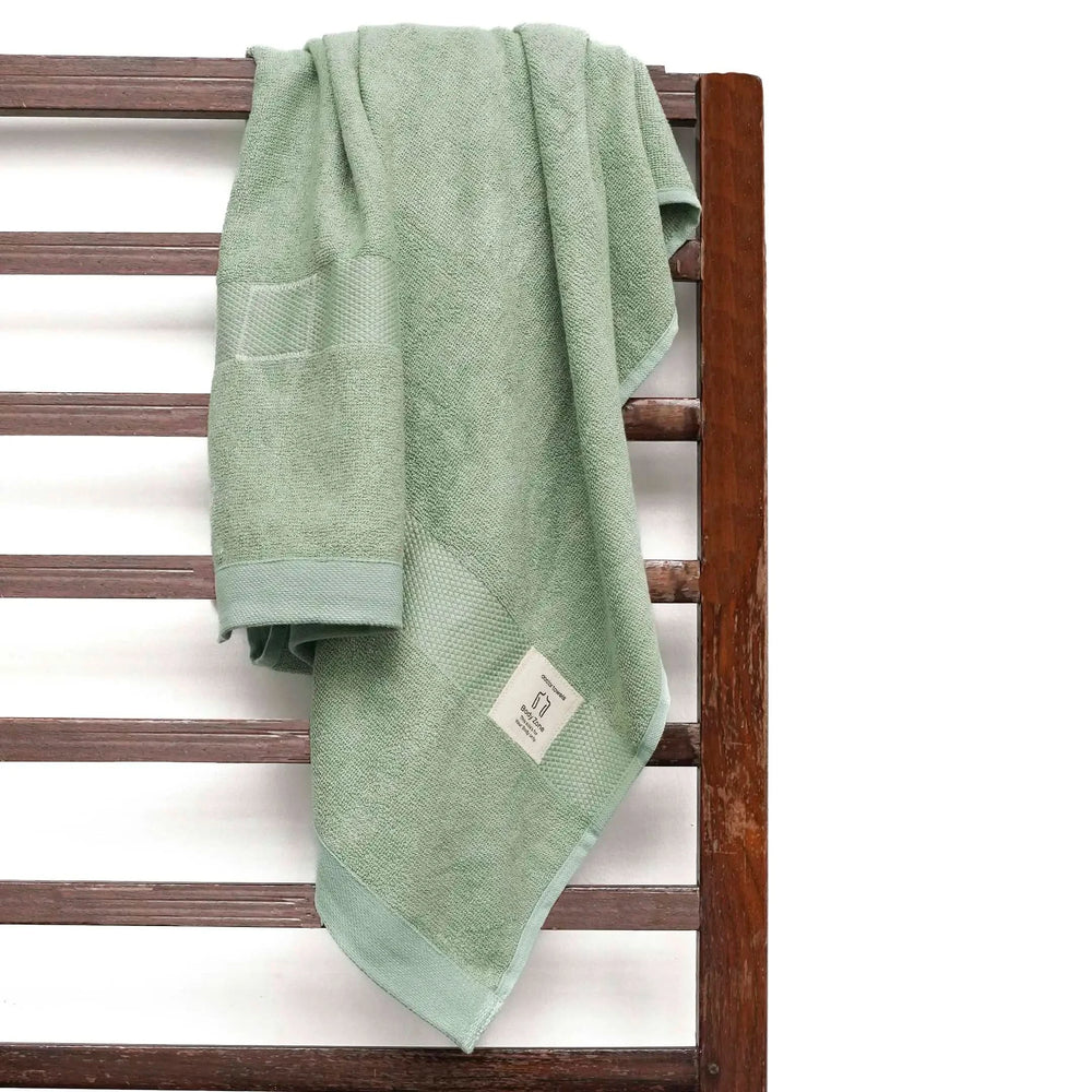 Green towel hanging on a wooden towel rack with a white background