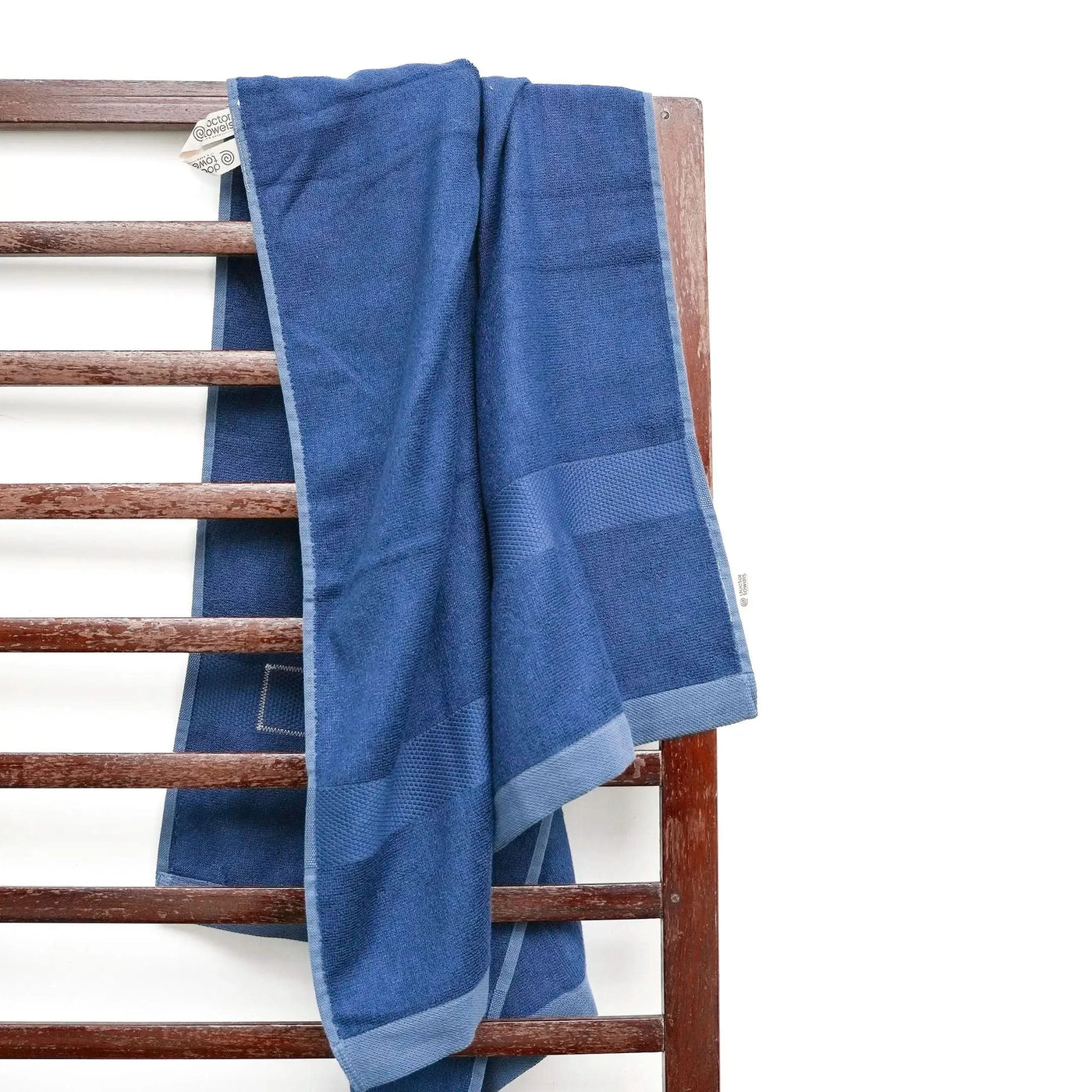 French blue towel draped over a wooden towel rack on a white background