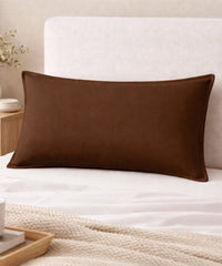 chocolate brown pillow on a bed with a neutral headboard and decor items.