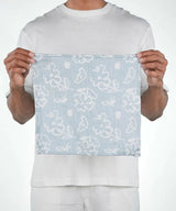 Person holding a light blue fabric with white floral patterns against a white background