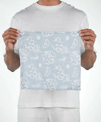 Person holding a light blue fabric with white floral patterns against a white background