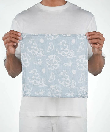 Person holding a light blue fabric with white floral patterns against a white background