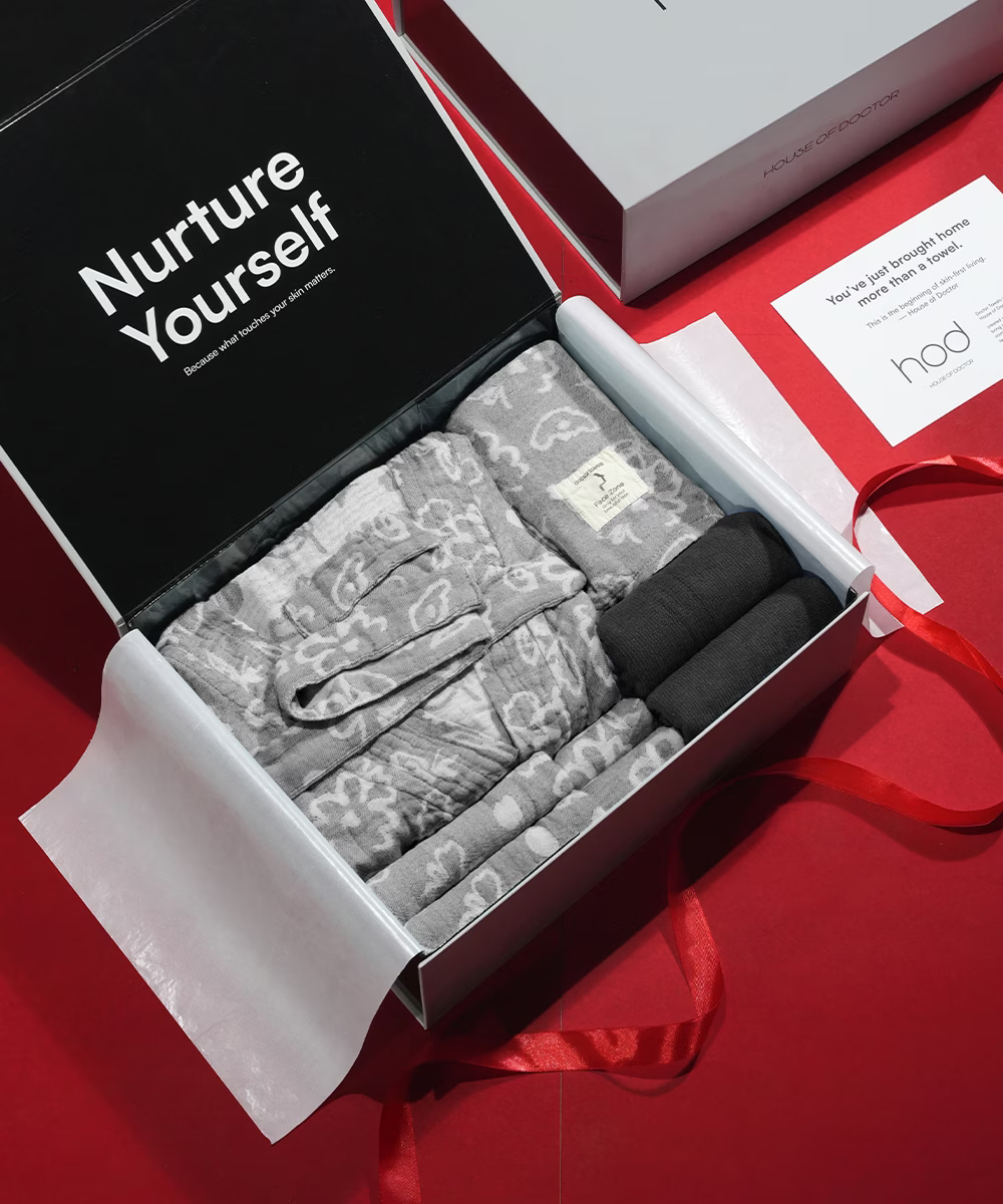 Open gift box with gray lace lingerie on a red surface, featuring 'Nurture Yourself' text.
