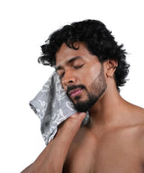 Man with a towel on his face against a white background