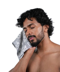 Man with a towel on his face against a white background