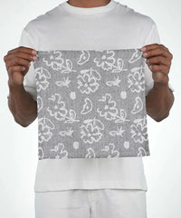 Person holding a gray fabric with white floral pattern against a white background