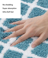Blue and white checkered bath mat with a hand touching it, highlighting features like no shedding, super absorption, and ultra soft feel.