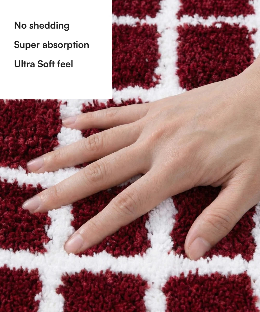 Red and white checkered bath mat with a hand touching it, highlighting features like no shedding, super absorption, and ultra soft feel.