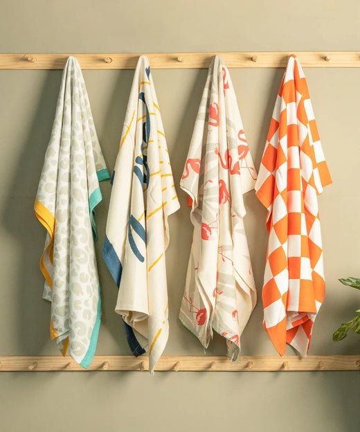 Four Thirsty towels hanging on a wooden wall.